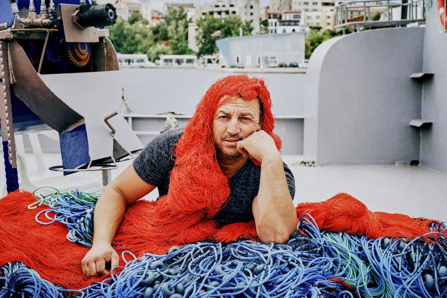 Funny photo of fisherman wearing fishing net as if it was his hair