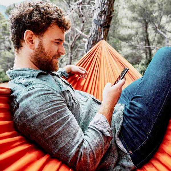 Medium MS PPT MS Word Newsletter A man looking at this phone while relaxing on an orange hammock in the forest