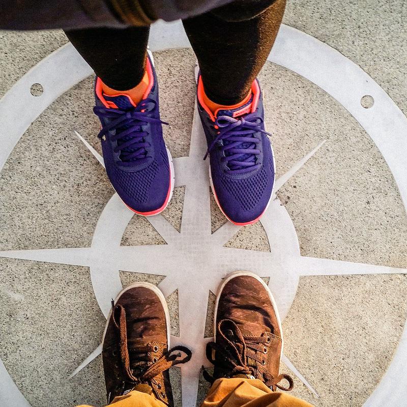 Overhead view of two people standing on a compass sign on the floor